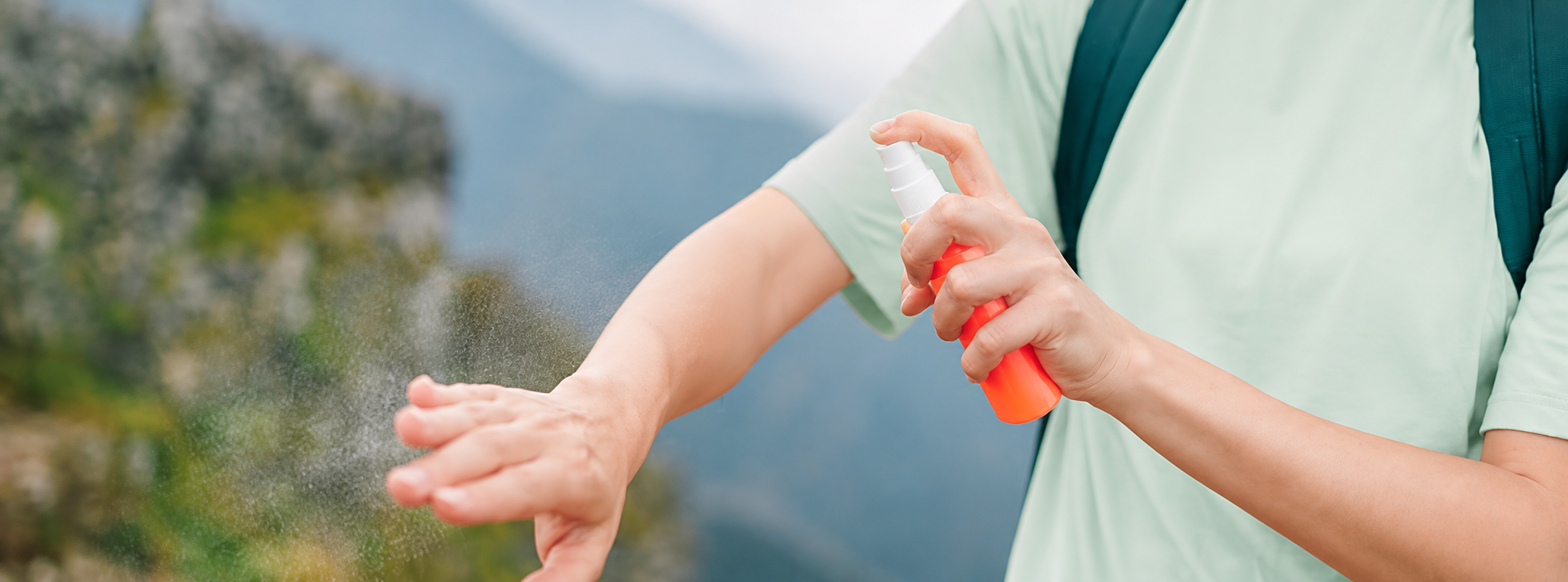 Kvinde på vandretur sprayer myggespray på armen