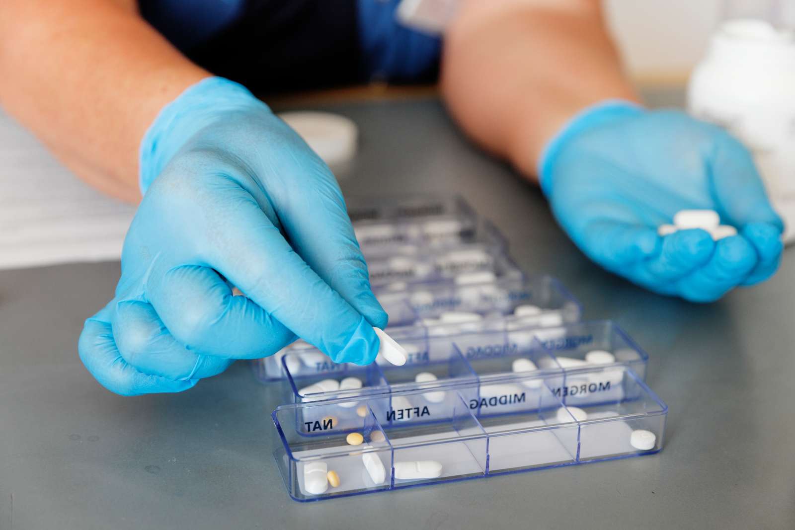 Hænder der doserer medicin i æsker