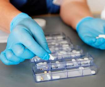 Hænder der doserer medicin i æsker