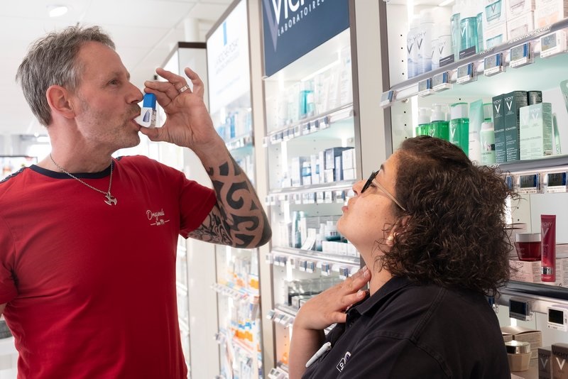 Medarbejder på apoteket instruerer en kunde i brugen af en astmainhalator